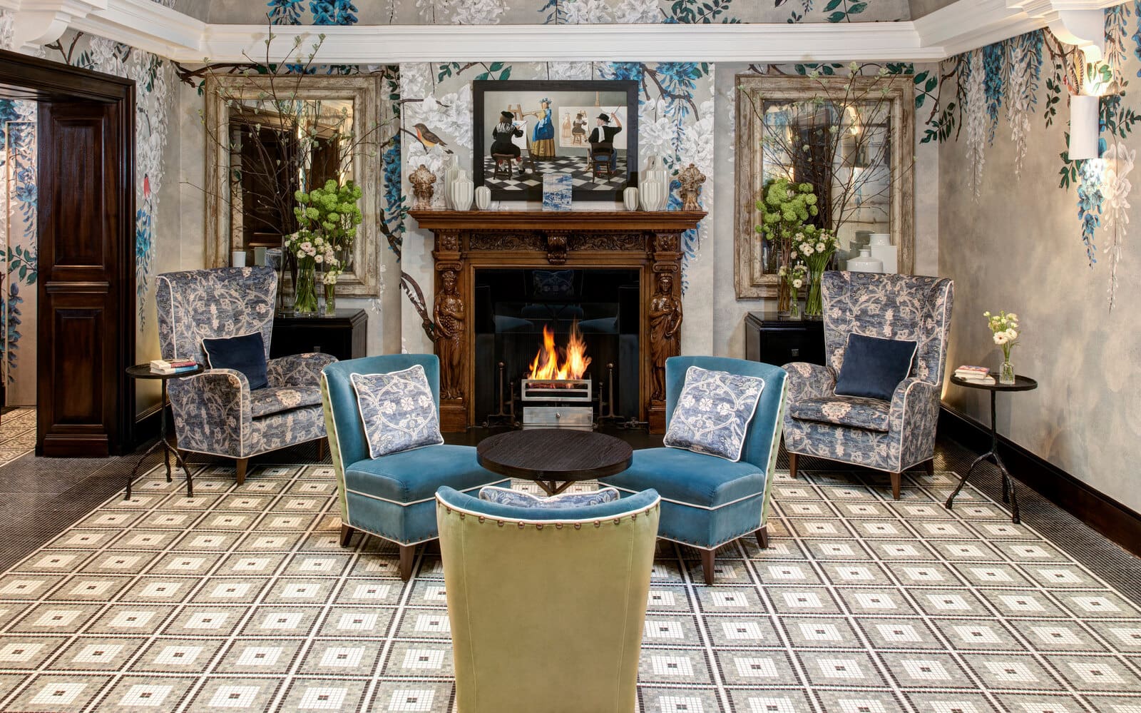 Blue floral wingback chairs around a lit fireplace in the lounge at Brown's Hotel, Mayfair